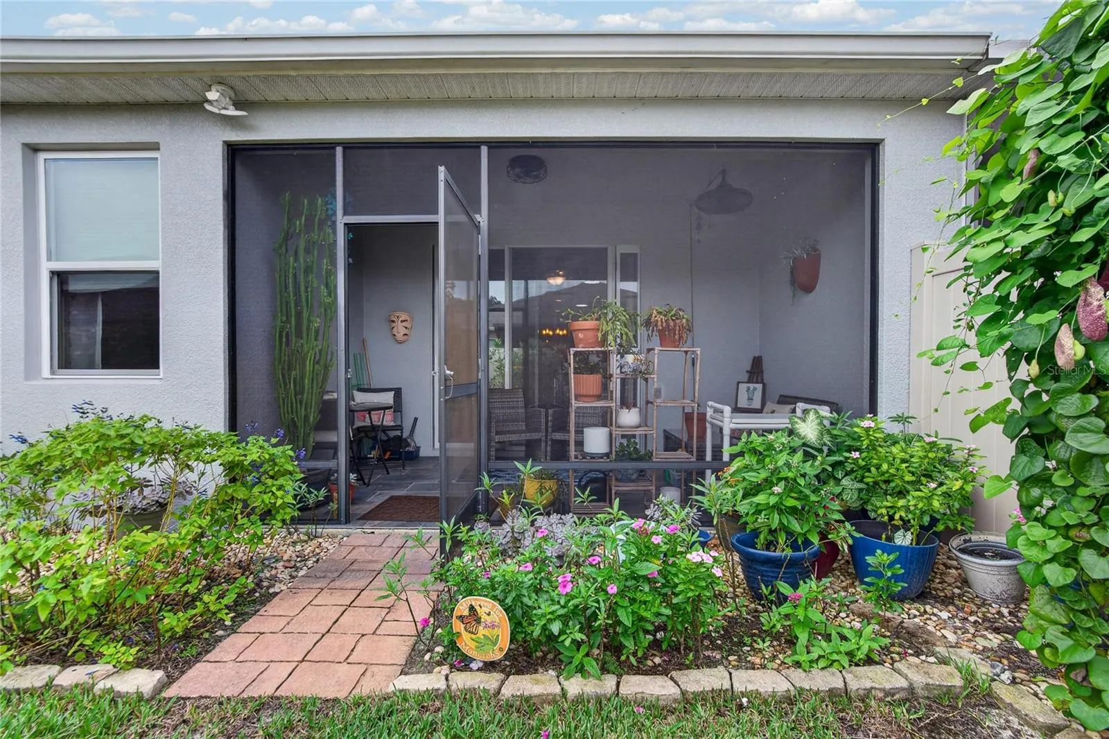 The screened lanai opens to established garden beds, creating an easy connection between indoor comfort and outdoor color.