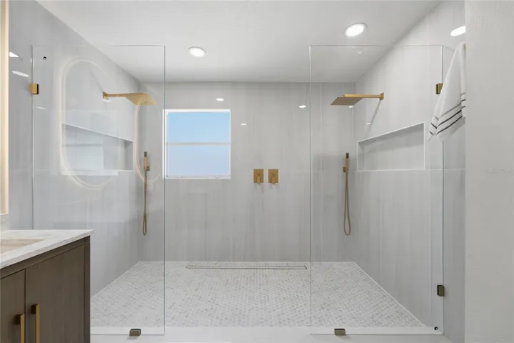 Oversized walk-in shower with largeporcelain tile and dual rainfall heads