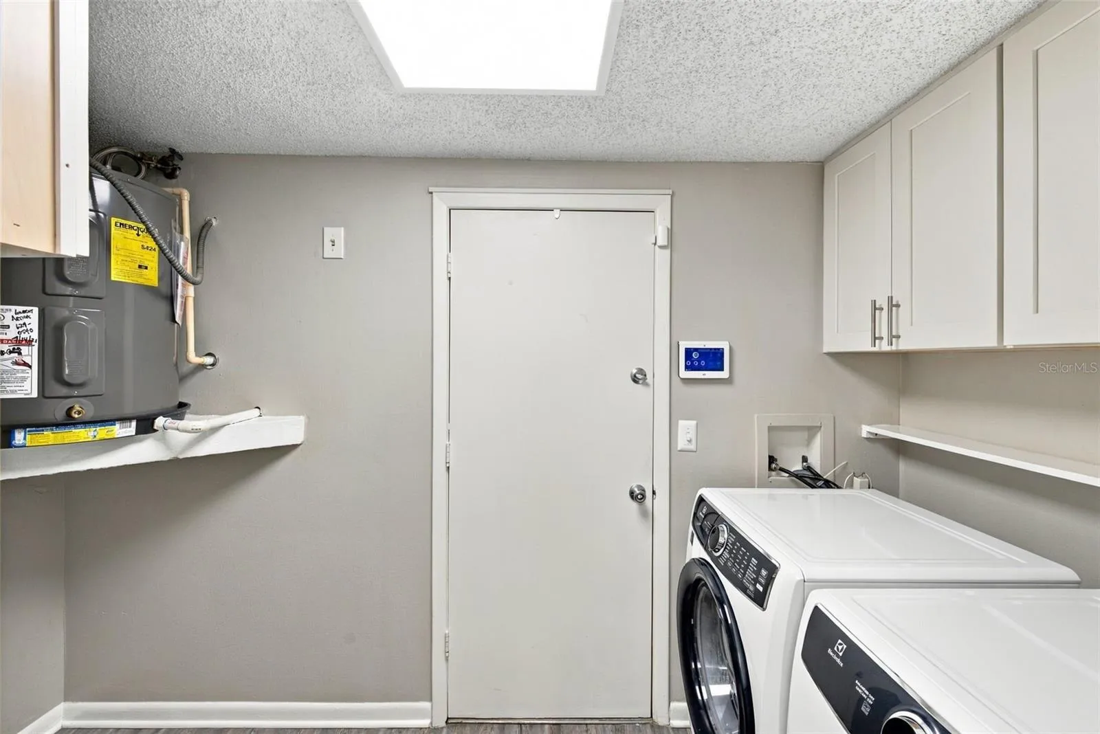 Large laundry room with cabinetry.  Door to garage beyond.
