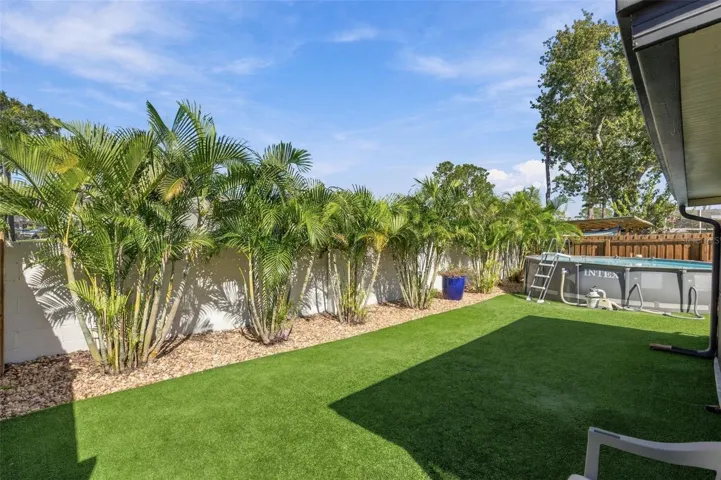 Large backyard with newer above-ground pool, beautiful landscaping and low-maint. artificial turf