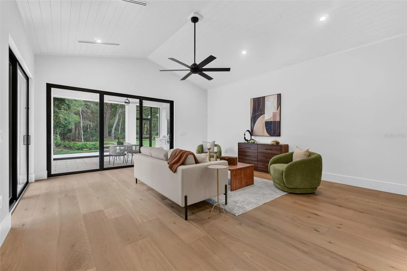 Game room features a wet bar with beverage refrigerator and two large sliding glass doors that provide direct access to pool and covered lanai