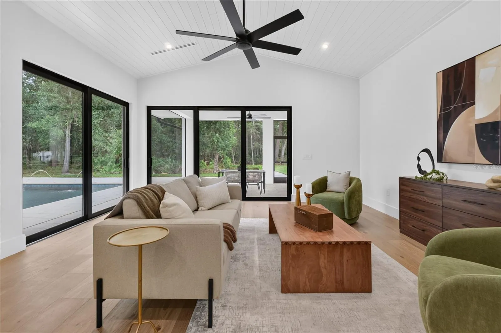 Game room features a wet bar with beverage refrigerator and two large sliding glass doors that provide direct access to pool and covered lanai