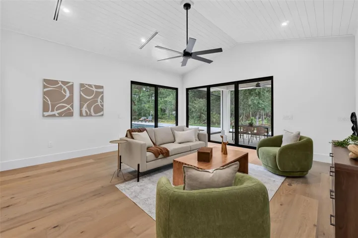 Game room features a wet bar with beverage refrigerator and two large sliding glass doors that provide direct access to pool and covered lanai