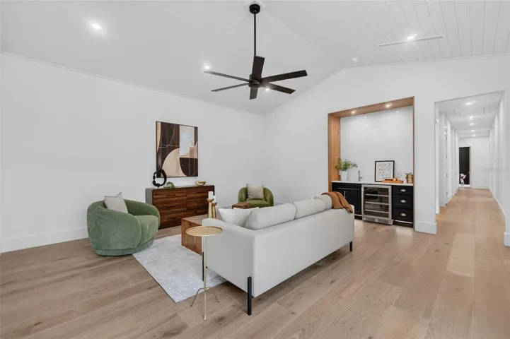 Game room features a wet bar with beverage refrigerator and two large sliding glass doors that provide direct access to pool and covered lanai