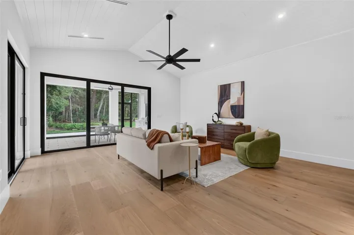 Game room features a wet bar with beverage refrigerator and two large sliding glass doors that provide direct access to pool and covered lanai