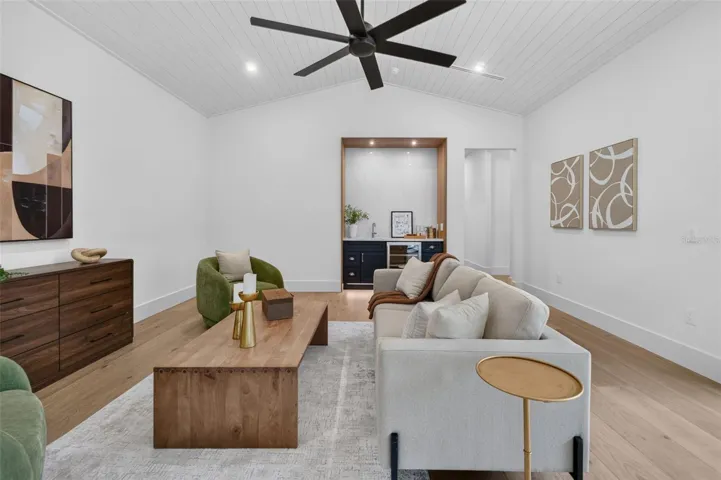 Game room features a wet bar with beverage refrigerator and two large sliding glass doors that provide direct access to pool and covered lanai