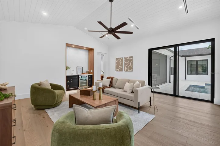Game room features a wet bar with beverage refrigerator and two large sliding glass doors that provide direct access to pool and covered lanai