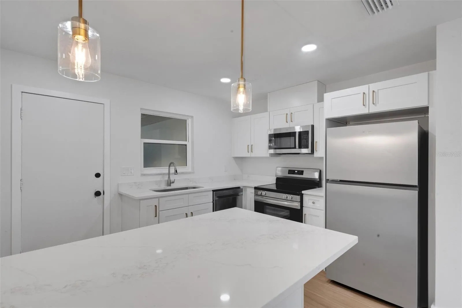 kitchen with door to back space with new appliances.  microwave is open to outside