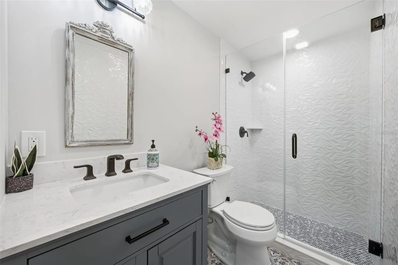 Beautifully updated main bath featuring sculptural 3D wave tile, frameless glass shower.