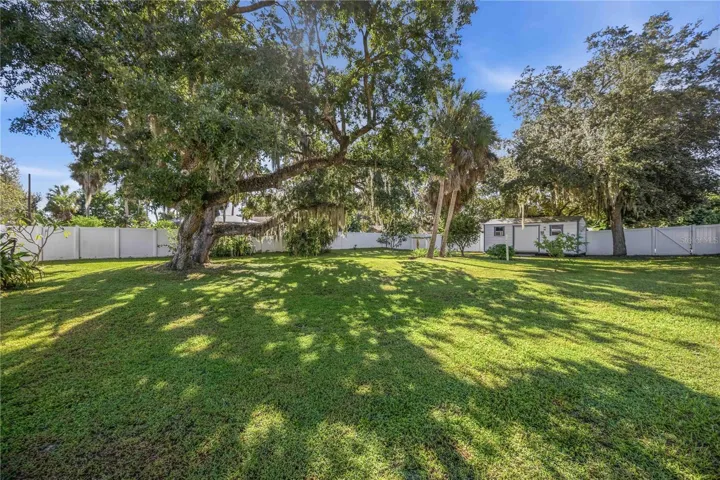 Large yard with mature oak trees and vinyl fencing