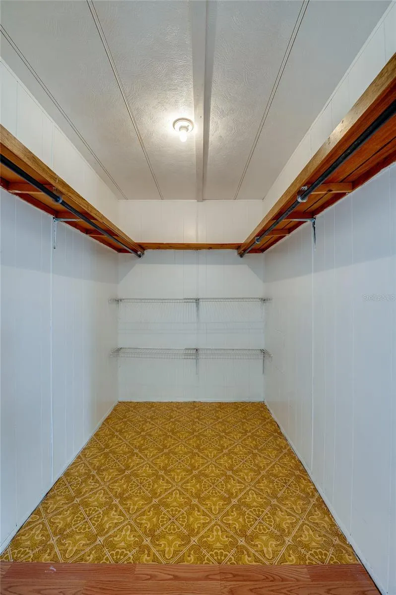Generously sized walk-in closet provides hanging space and additional shelving for organized storage.