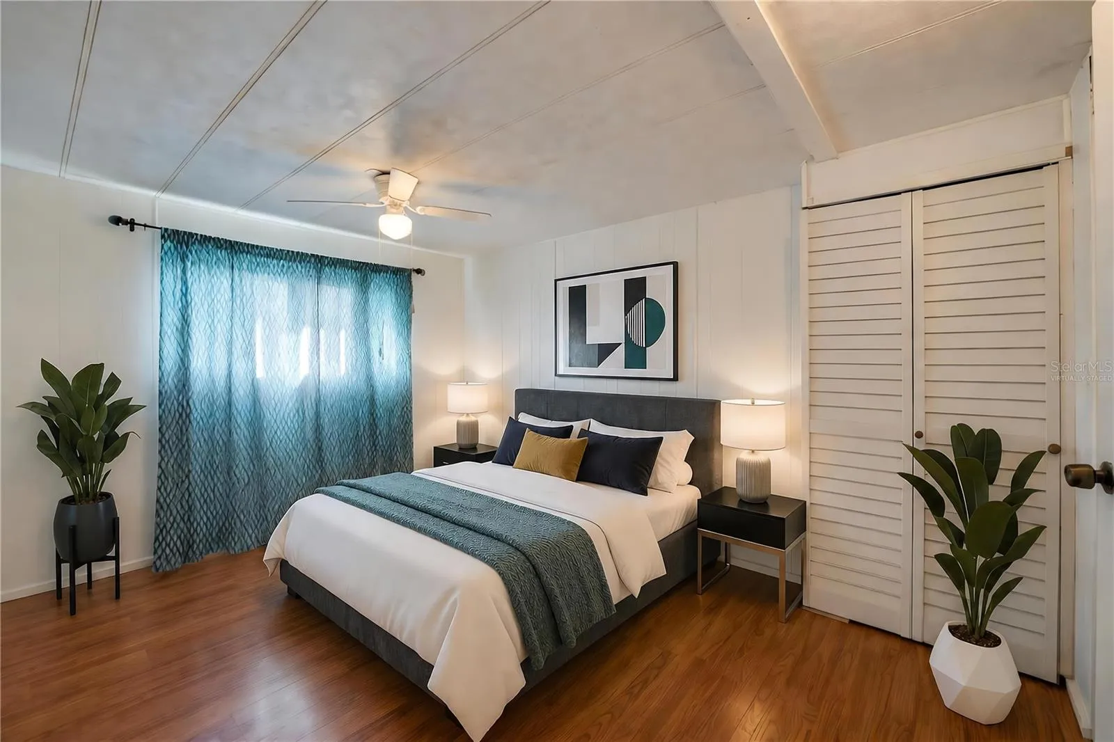 Virtually Staged - Bright, versatile bedroom with paneled walls, a ceiling fan with light, a large window for natural light, and a louvered-door closet.