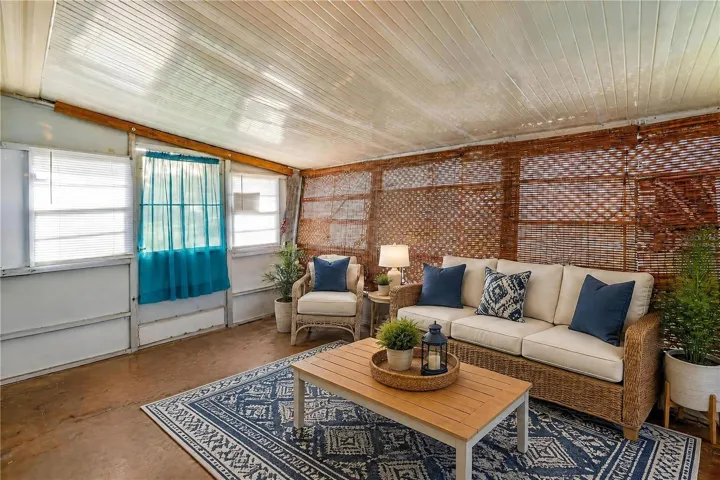 Virtually Staged - Expansive enclosed porch offers a flexible bonus space with numerous windows and woven shades for filtered natural light.