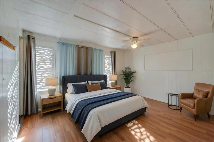 Virtually Staged - Spacious bedroom with paneled walls, a ceiling fan, and multiple windows that bring in abundant natural light.