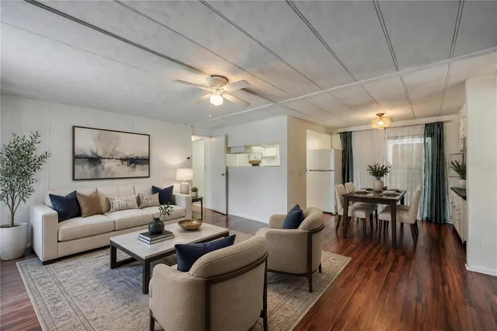 Virtually Staged - Wide-angle view highlights the open flow between the living, dining, and kitchen spaces, complemented by natural light from the large window.