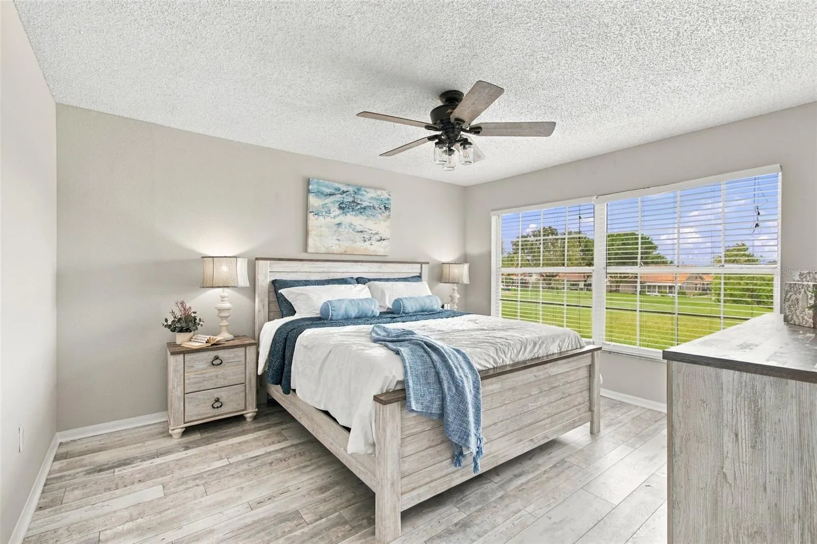 Spacious Primary Bedroom with Views of the Golf Course.  All furniture in this room will convey with the sale should the Buyer want it! Note: Bedding, lamps, picture and accessories are staged and not included in sale - Only furniture