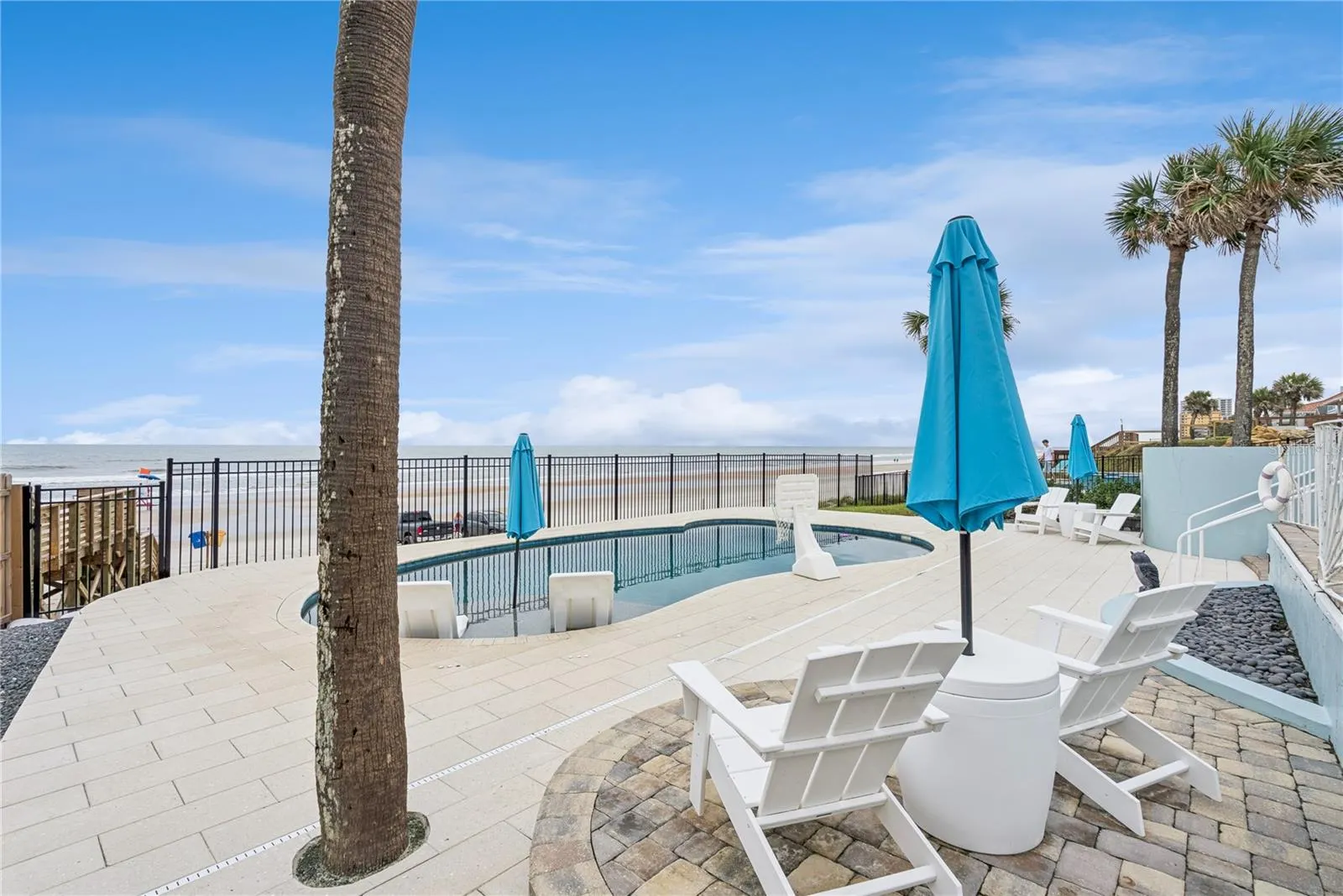 New oceanfront pool installed in 2024, featuring heating, a sun shelf, bubblers, and a 7-foot-deep end, with expansive patio space and panoramic Atlantic views.