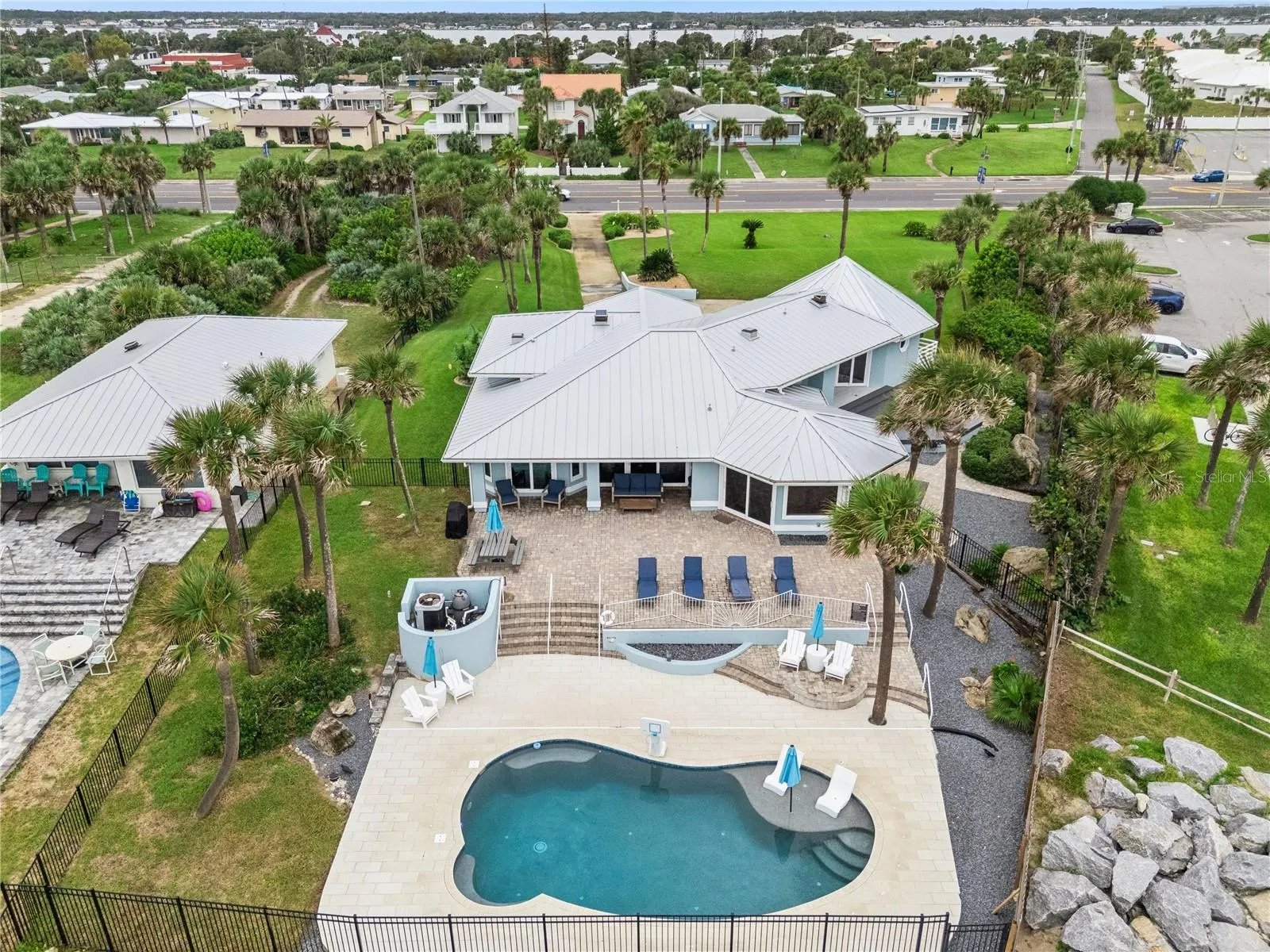 New oceanfront pool installed in 2024, featuring heating, a sun shelf, bubblers, and a 7-foot-deep end, with expansive patio space and panoramic Atlantic views.