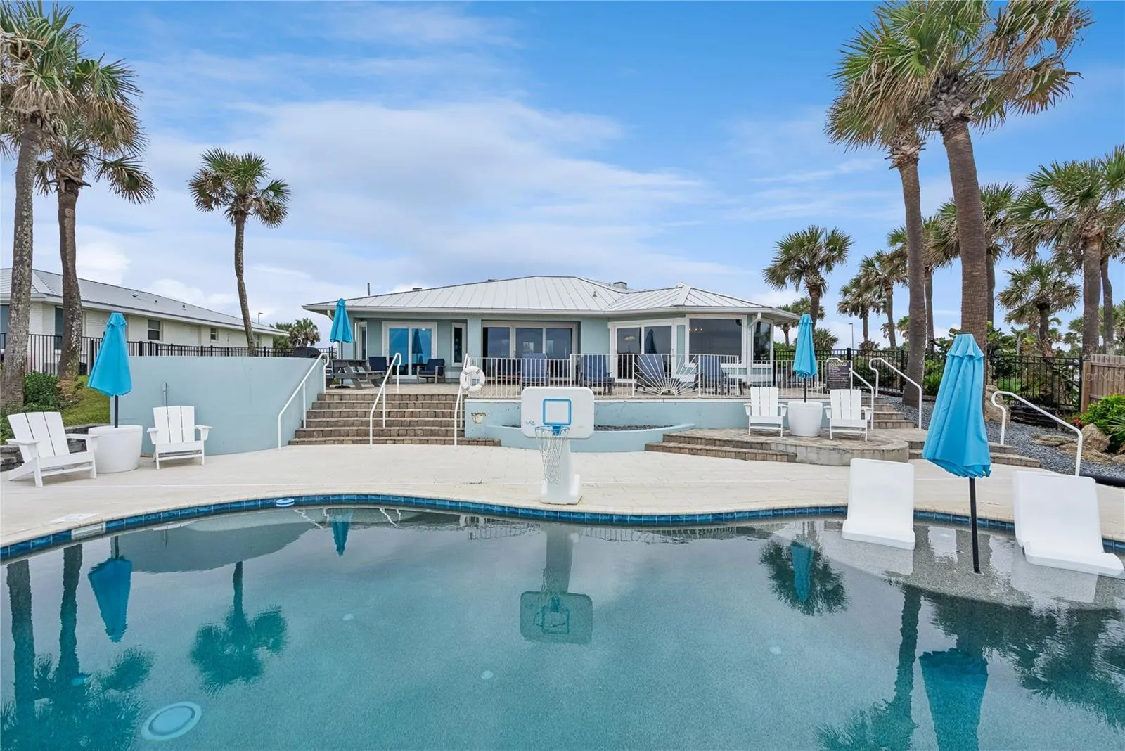 New oceanfront pool installed in 2024, featuring heating, a sun shelf, bubblers, and a 7-foot-deep end, with expansive patio space and panoramic Atlantic views.