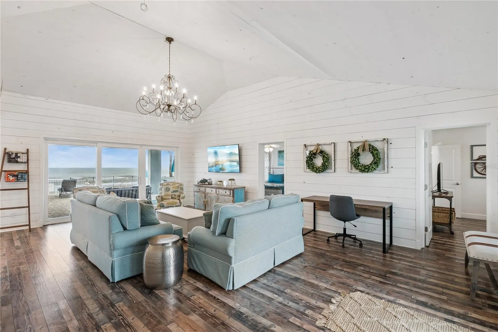 Sweeping Atlantic views take center stage in this bright family room, complemented by coastal furnishings and luxury vinyl plank flooring.