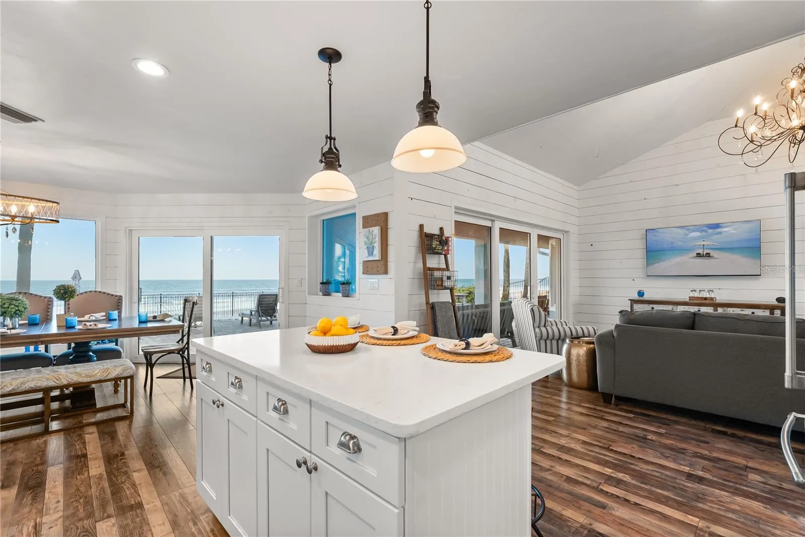 Spacious eat-in kitchen with stainless steel appliances, quartz countertops, breakfast bar seating, and beautiful ocean views—an inviting setting for casual meals and gathering.