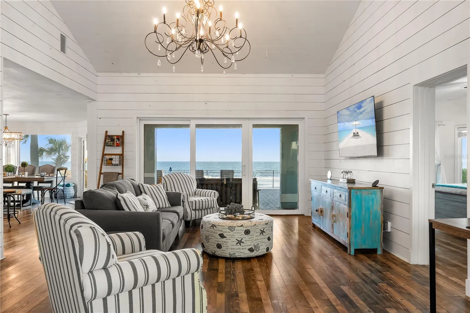 Sweeping Atlantic views take center stage in this bright family room, complemented by coastal furnishings and luxury vinyl plank flooring.