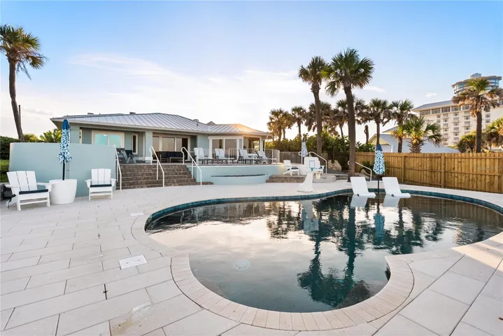 New oceanfront pool installed in 2024, featuring heating, a sun shelf, bubblers, and a 7-foot-deep end, with expansive patio space and panoramic Atlantic views