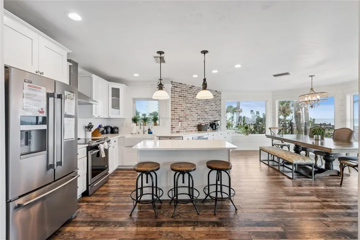 Spacious eat-in kitchen with stainless steel appliances, quartz countertops, breakfast bar seating, and beautiful ocean views—an inviting setting for casual meals and gathering.