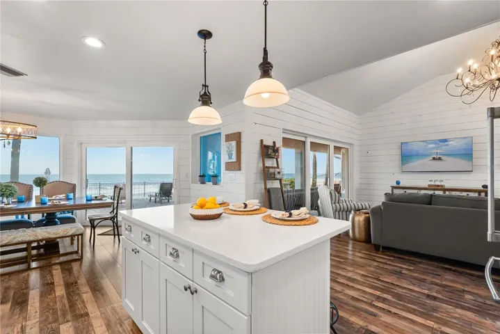 Spacious eat-in kitchen with stainless steel appliances, quartz countertops, breakfast bar seating, and beautiful ocean views—an inviting setting for casual meals and gathering.