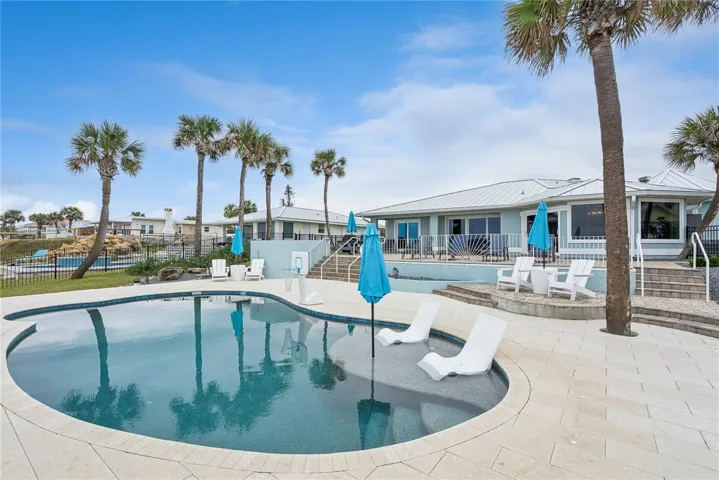 New oceanfront pool installed in 2024, featuring heating, a sun shelf, bubblers, and a 7-foot-deep end, with expansive patio space and panoramic Atlantic views.