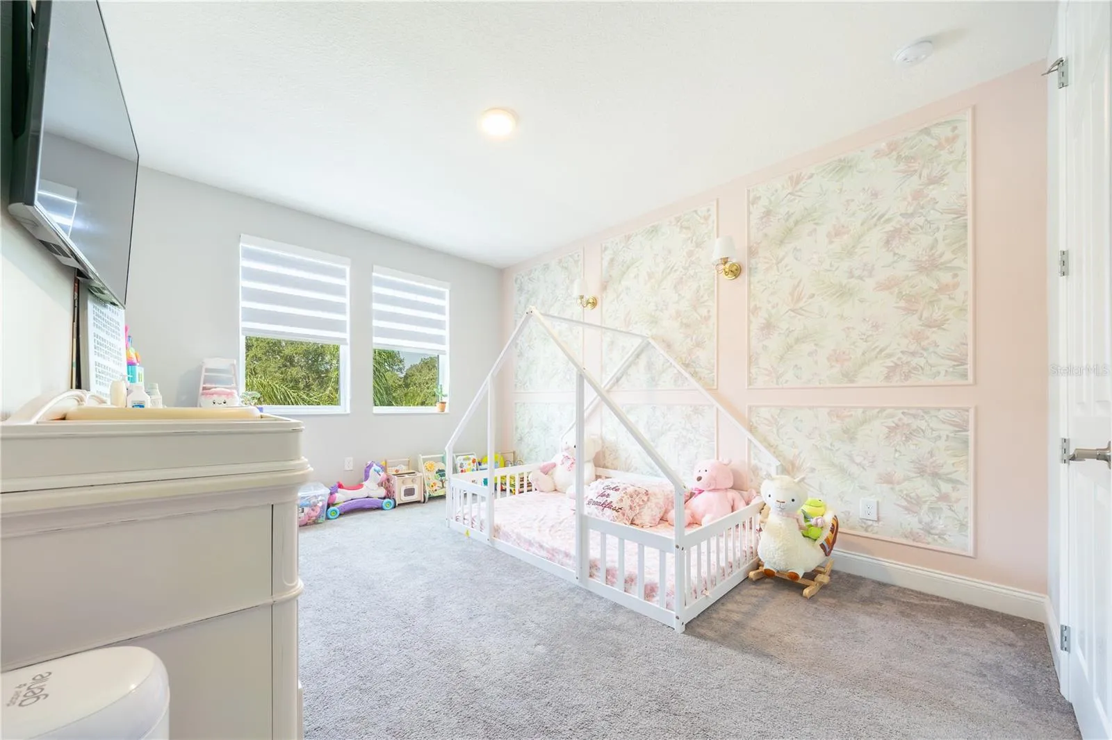 Charming bedroom with a floral accent wall, decorative sconces, and windows with lake views.