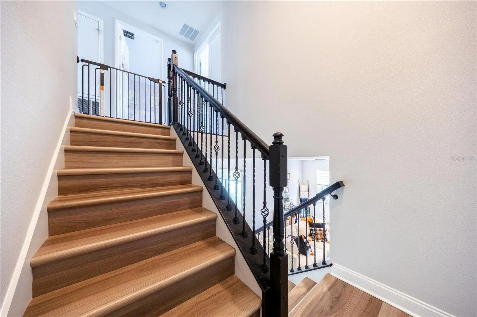 Elegant staircase with warm wood-look finishes and decorative metal railings leading to the upper level.