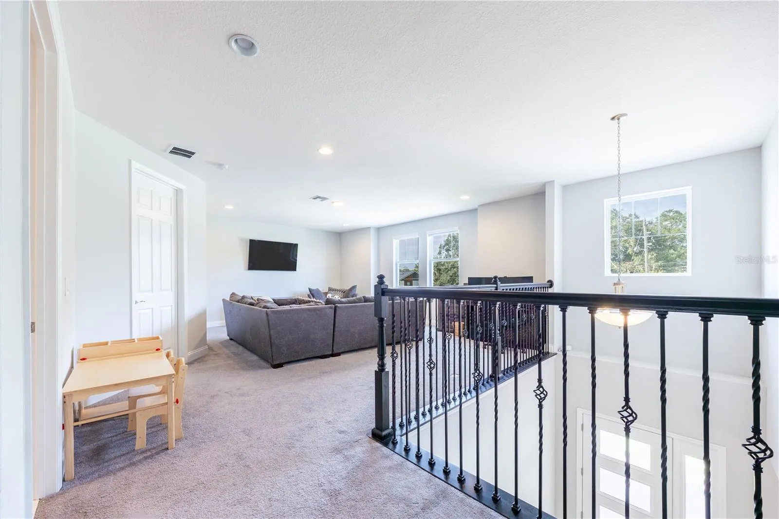 Spacious upstairs loft with a comfortable lounge area and decorative metal railings overlooking the foyer.