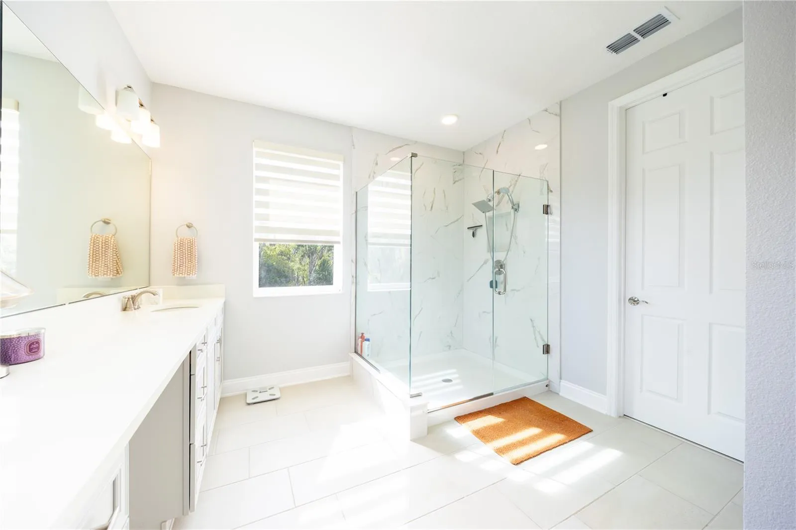 Refined primary bathroom with a frameless glass shower and marble-look tile finishes.