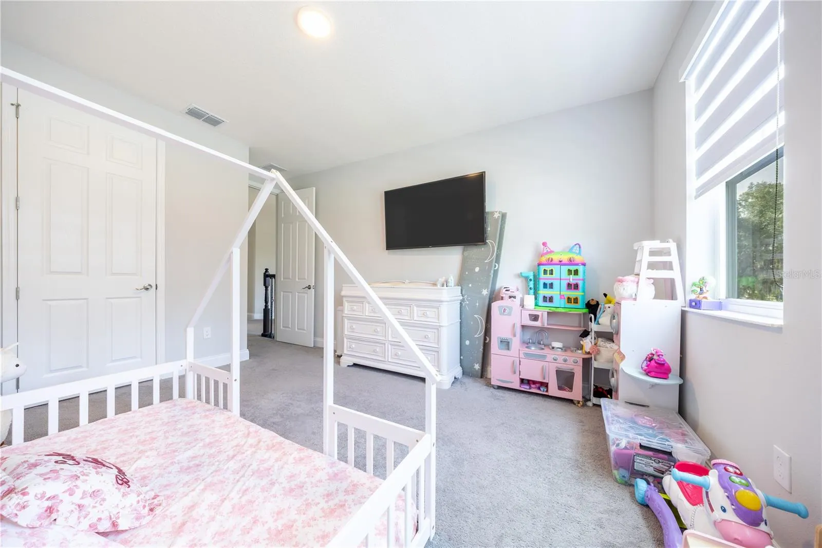 Comfortable bedroom with soft carpeting, a double-door closet, and space for a play area.