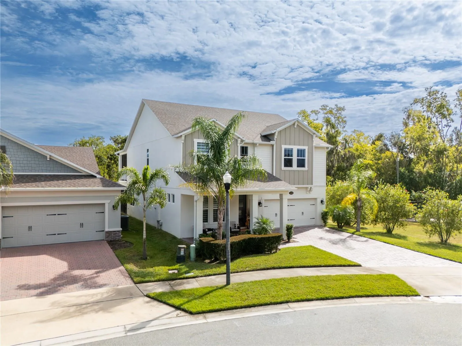 Elevated front view showcasing elegant curb appeal, tropical landscaping, and a two-car garage.