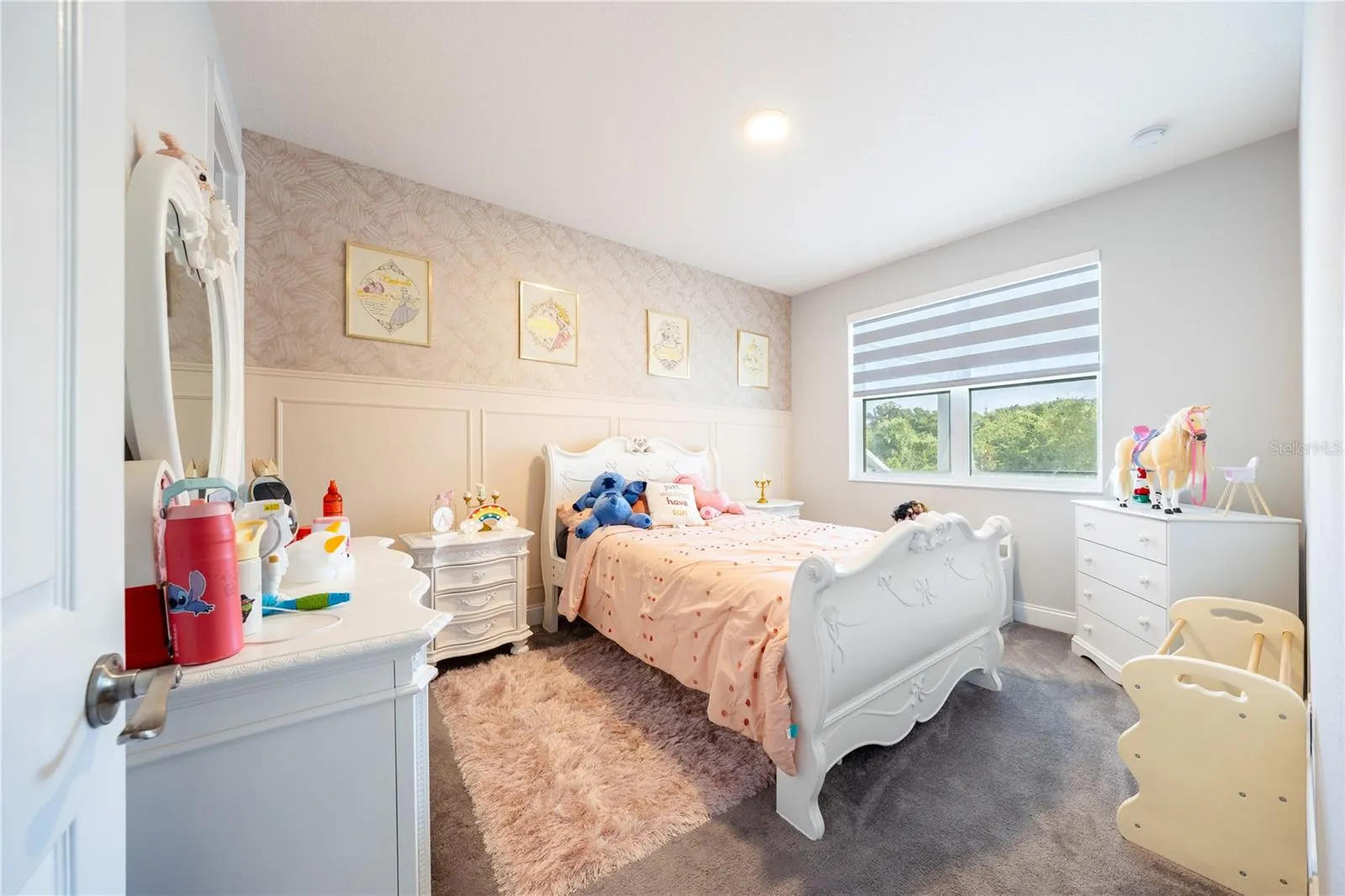 Inviting bedroom with a decorative accent wall, soft carpeting, and views of nature.
