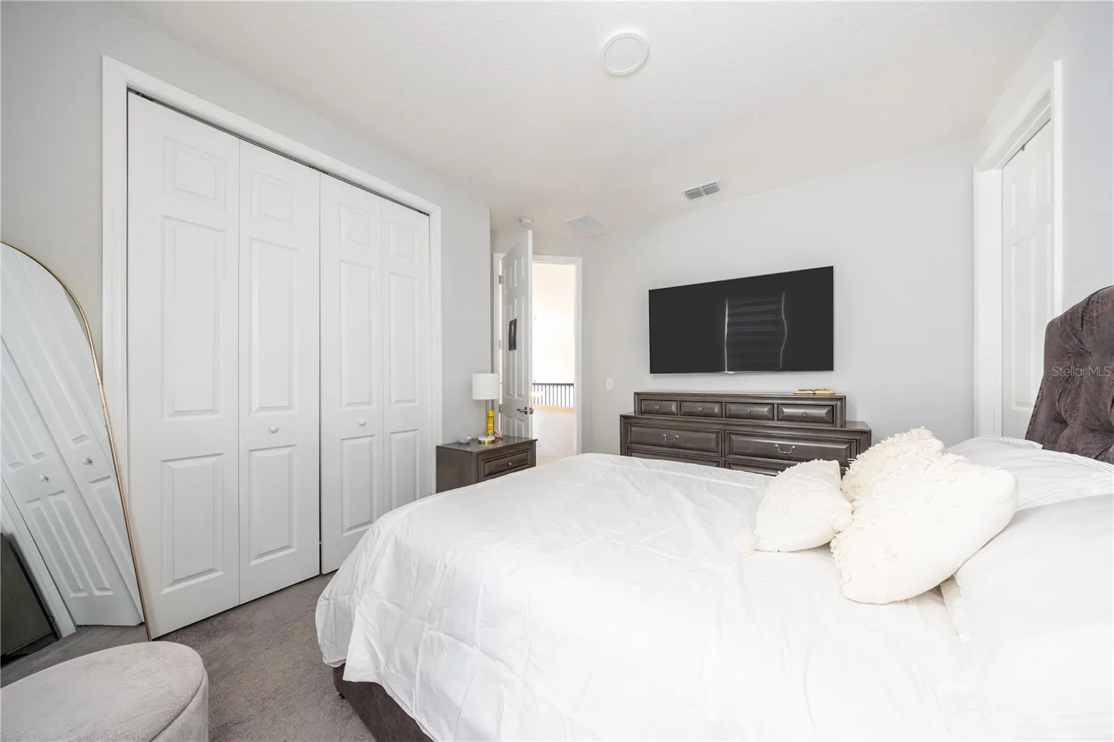 Comfortable bedroom with a spacious closet, soft carpeting, and a refined neutral palette.