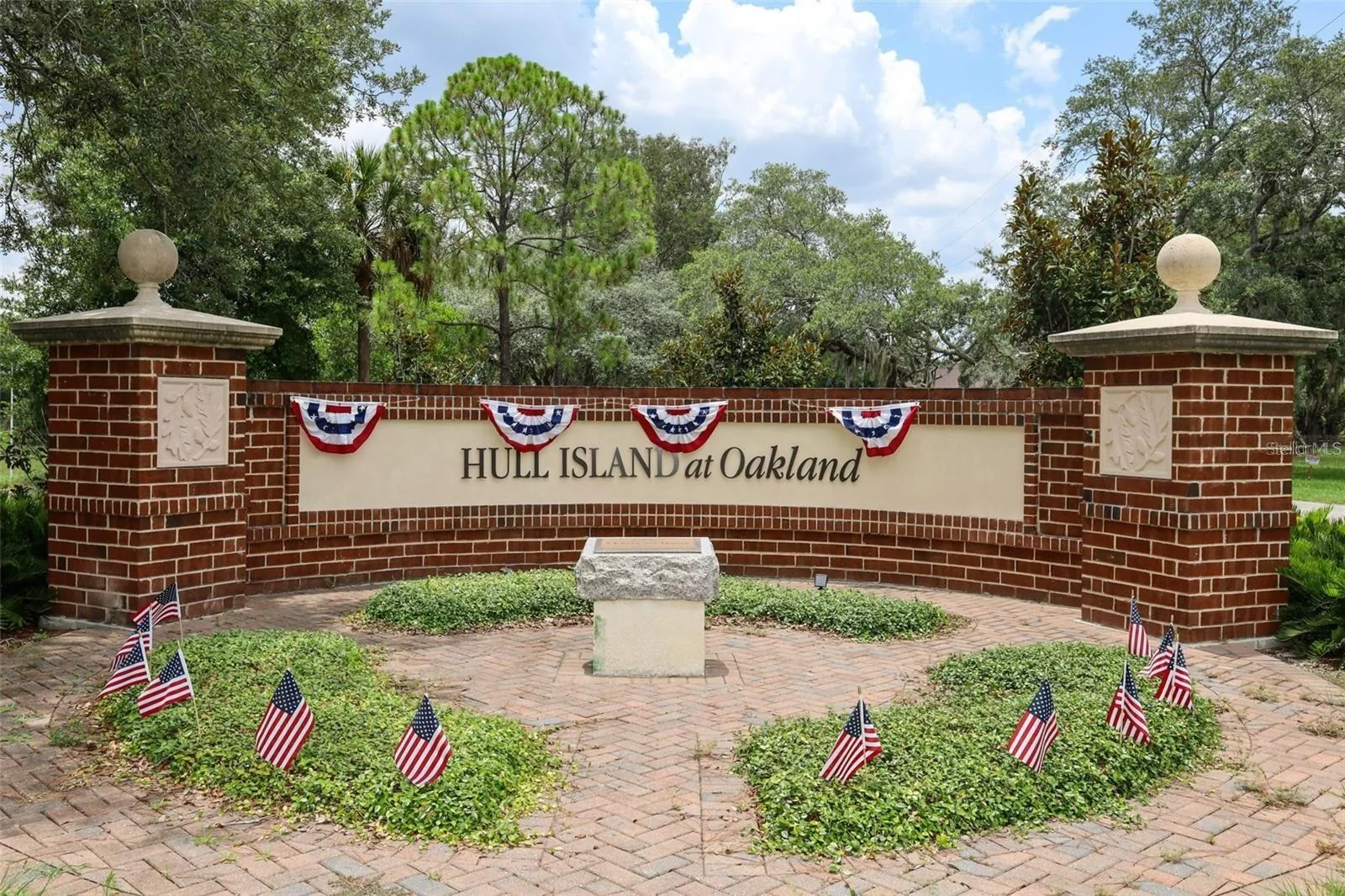 Welcome to Hull Island at Oakland, with a beautifully landscaped entrance framed by mature trees.