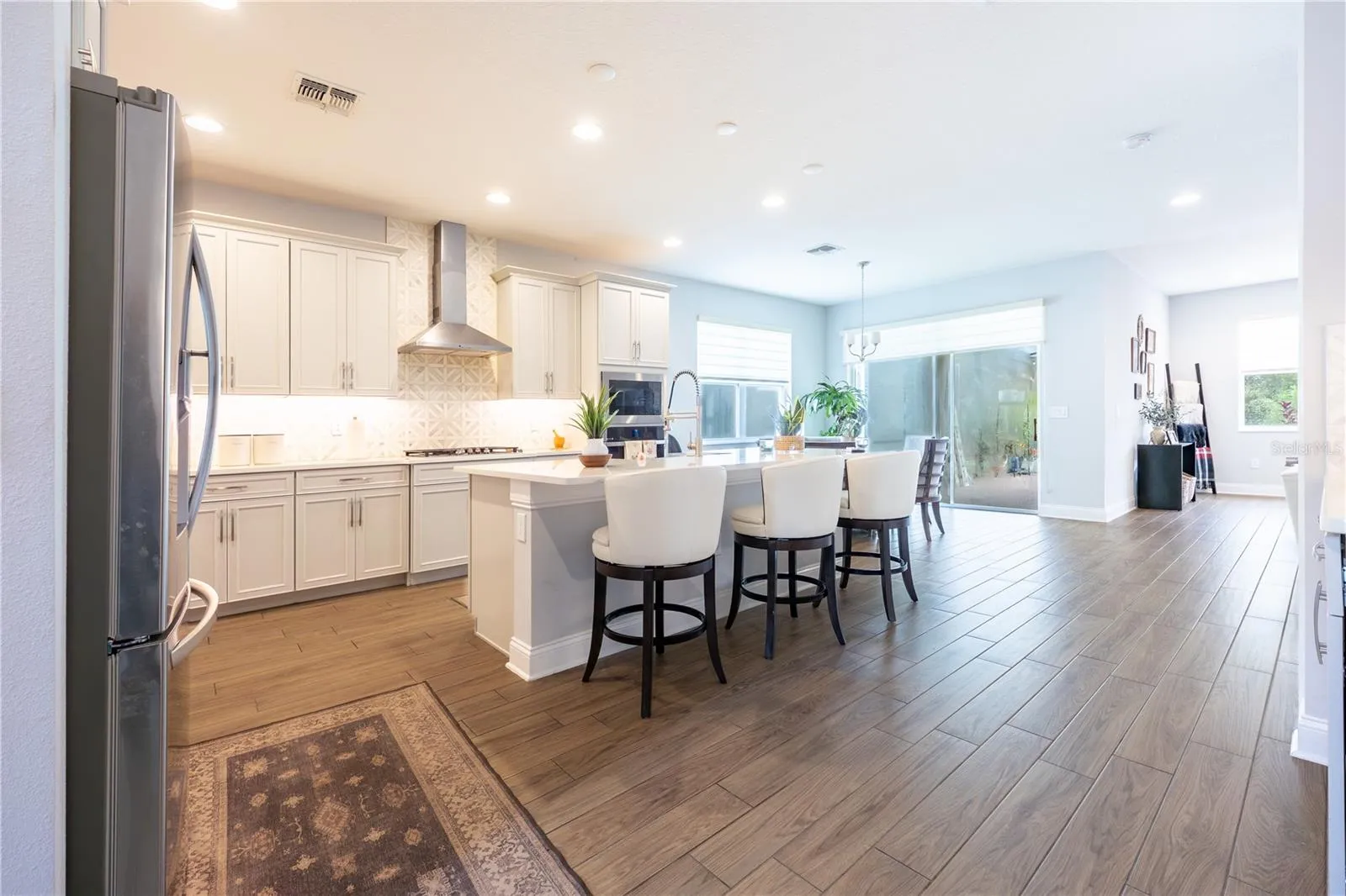 Open-concept kitchen with a generous island, stainless steel range hood, and easy access to the covered patio.
