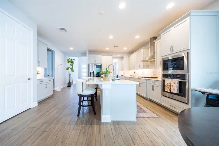 Elegant kitchen with white cabinetry, a spacious island with seating, and stainless steel appliances.