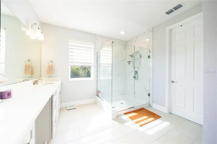 Refined primary bathroom with a frameless glass shower and marble-look tile finishes.