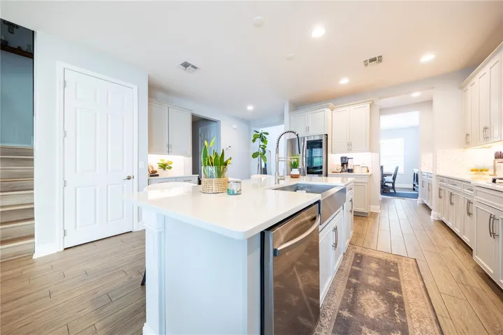 Spacious kitchen island featuring a stainless steel apron-front sink, pull-down faucet, and integrated dishwasher.
