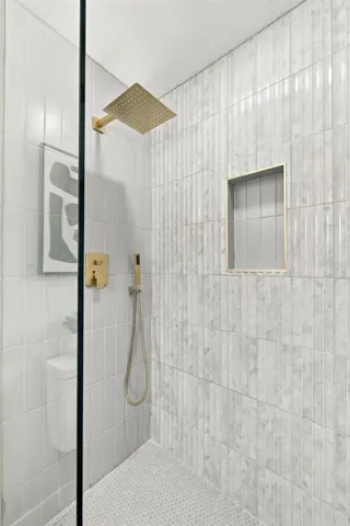 Beautiful Gold hardware with rainfall shower head and hand shower, shower niche and seamless glass entry