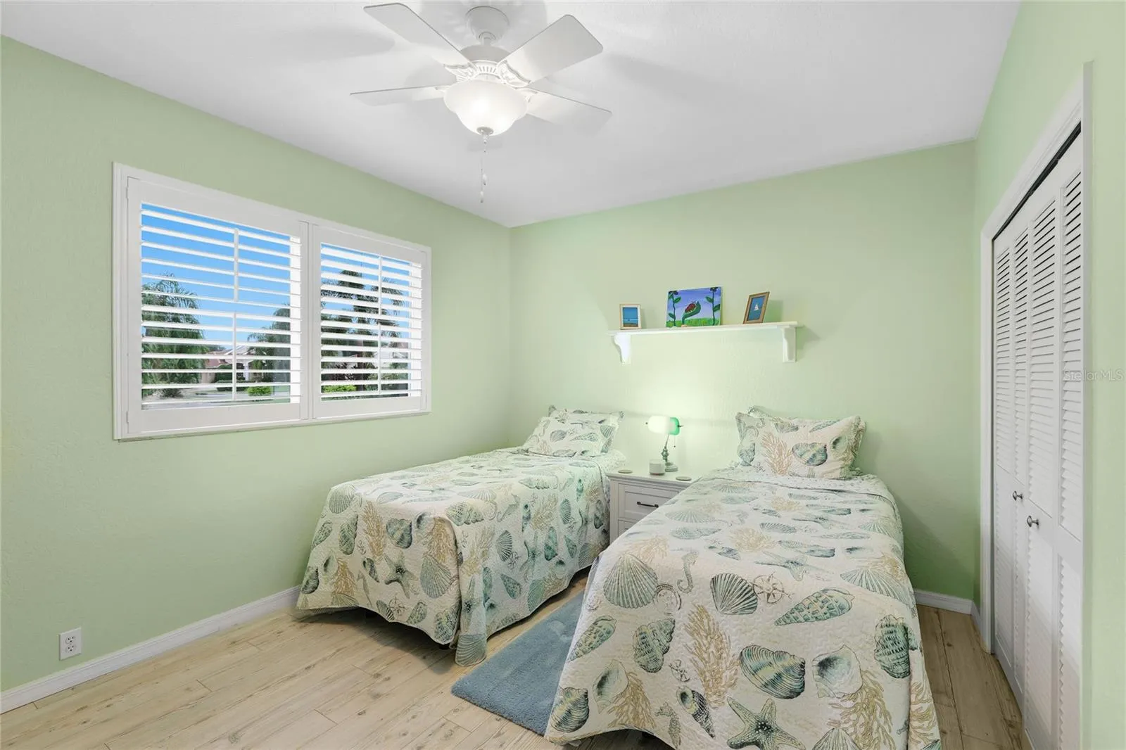 Guest bedroom two features custom louvered shutters, ceiling fan, and baseboard trim.