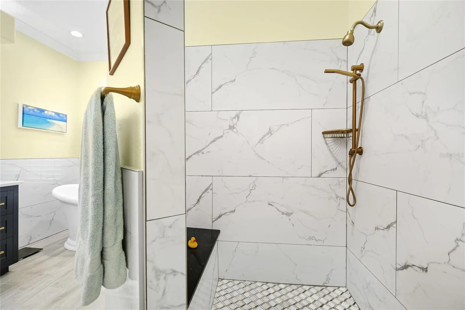 Primary bathroom walk-in shower with custom tile, updated plumbing fixtures, and built-in bench.