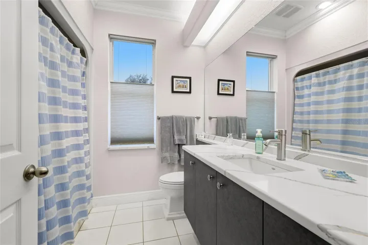 Guest bathroom features tile flooring, solid surface countertop, crown molding, updated plumbing fixtures, and Toto toilet.