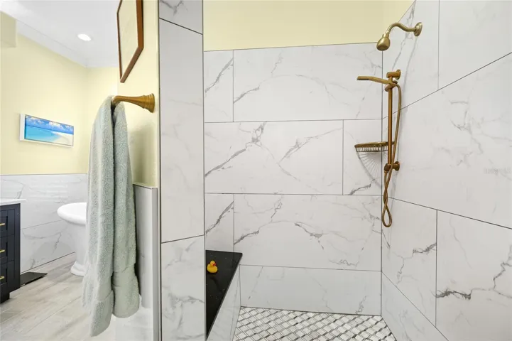 Primary bathroom walk-in shower with custom tile, updated plumbing fixtures, and built-in bench.