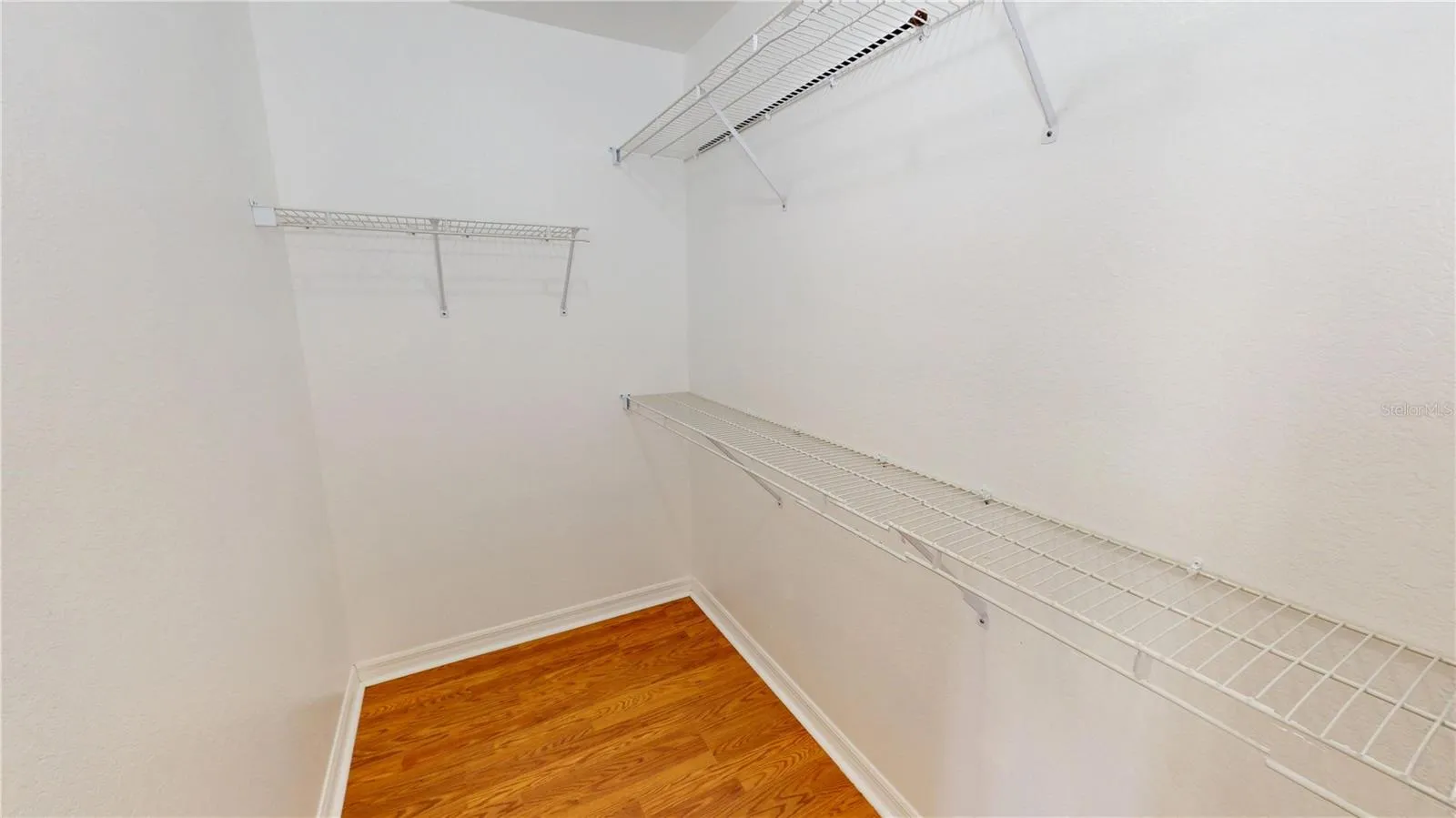 Walk in main bedroom closet includes multiple hanging shelves.