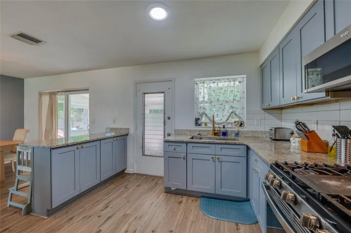 Well-appointed kitchen setup complete with an electric range stove, stainless steel appliances, granite counters, and direct outdoor access.